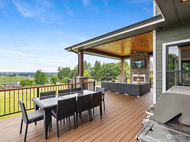 deck featuring area for grilling, outdoor dining space, and an outdoor living space with a fireplace