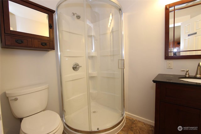 bathroom featuring vanity, toilet, and a shower with door