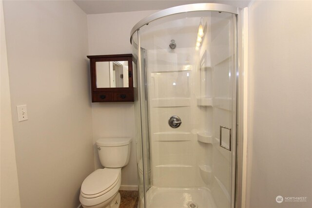 bathroom featuring an enclosed shower and toilet