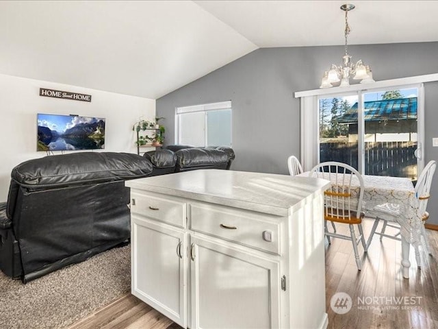 kitchen featuring an inviting chandelier, vaulted ceiling, hanging light fixtures, light wood-type flooring, and white cabinets