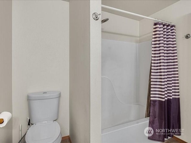 bathroom with shower / bath combination with curtain and toilet