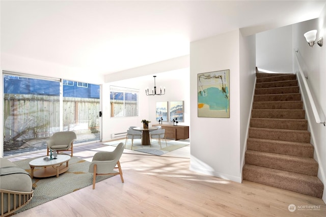 living room with a baseboard heating unit, light hardwood / wood-style flooring, and a notable chandelier