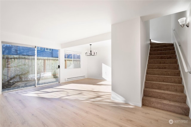 interior space with an inviting chandelier, baseboard heating, and light hardwood / wood-style flooring