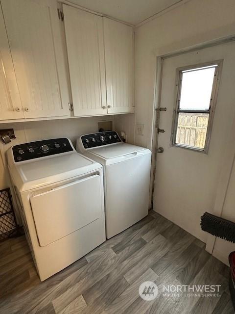 laundry area featuring washing machine and dryer, cabinets, and light wood-type flooring