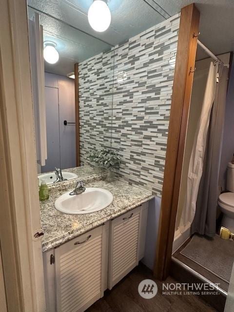 bathroom featuring vanity, a shower with shower curtain, backsplash, and toilet