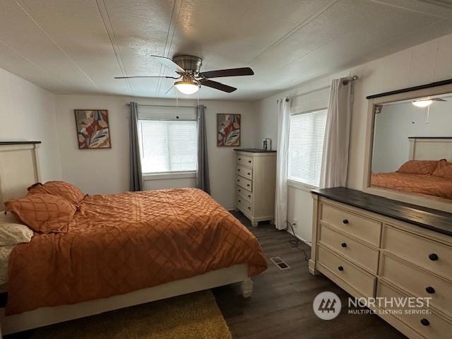 bedroom with multiple windows, dark hardwood / wood-style floors, and ceiling fan