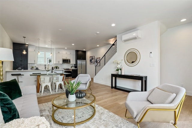 living room with a wall mounted air conditioner and light hardwood / wood-style flooring