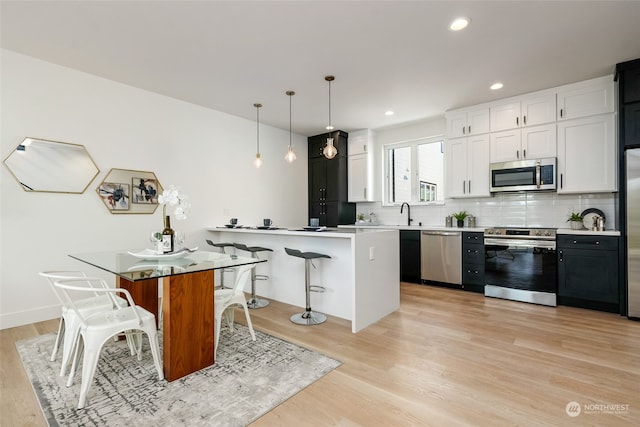 kitchen featuring a breakfast bar, white cabinetry, a center island, appliances with stainless steel finishes, and pendant lighting