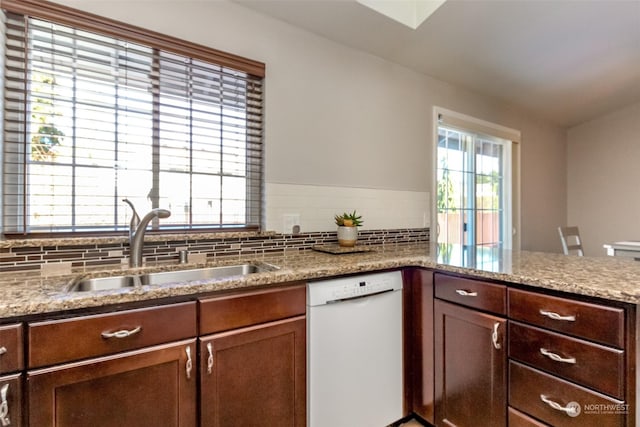 kitchen with tasteful backsplash, sink, light stone counters, and white dishwasher