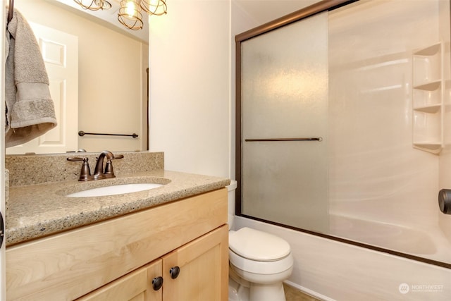 full bathroom with vanity, bath / shower combo with glass door, and toilet