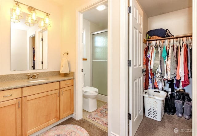 bathroom featuring vanity, a shower with shower door, and toilet