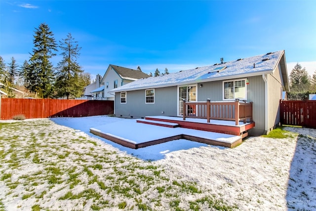 snow covered rear of property with a wooden deck