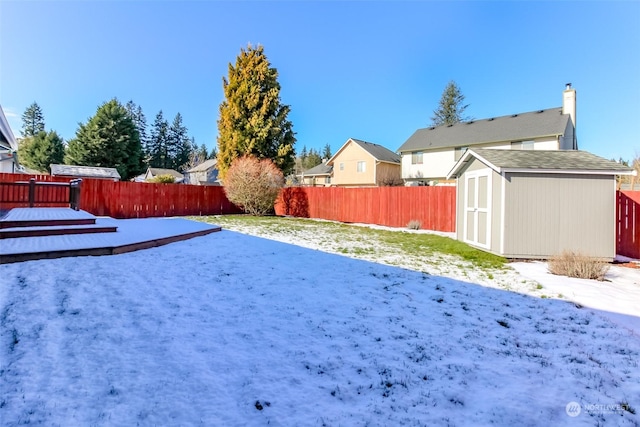 yard covered in snow with a deck and a shed