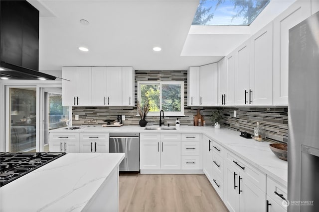 kitchen with sink, stainless steel appliances, white cabinets, and light stone countertops