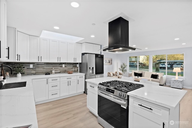 kitchen with stainless steel appliances, island exhaust hood, sink, and white cabinets