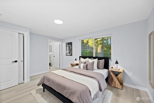 bedroom featuring ensuite bath and light wood-type flooring