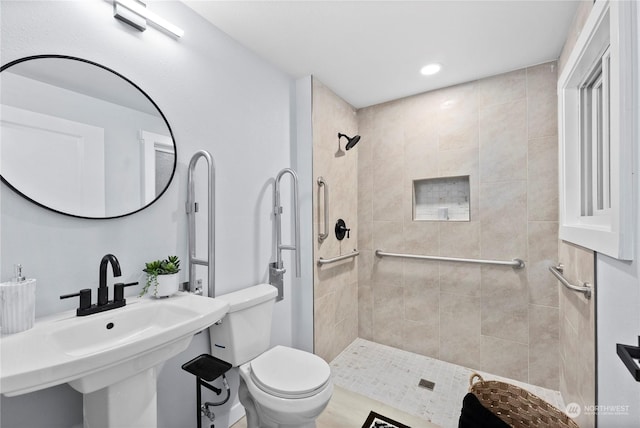 bathroom with tiled shower, toilet, and sink