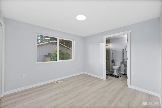 unfurnished bedroom with connected bathroom and light wood-type flooring