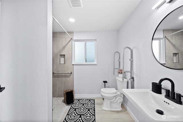 bathroom with wood-type flooring, toilet, sink, and a tile shower