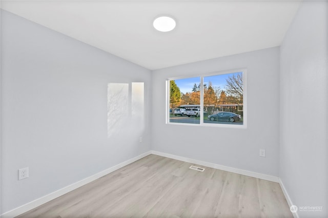 unfurnished room featuring lofted ceiling and light hardwood / wood-style floors