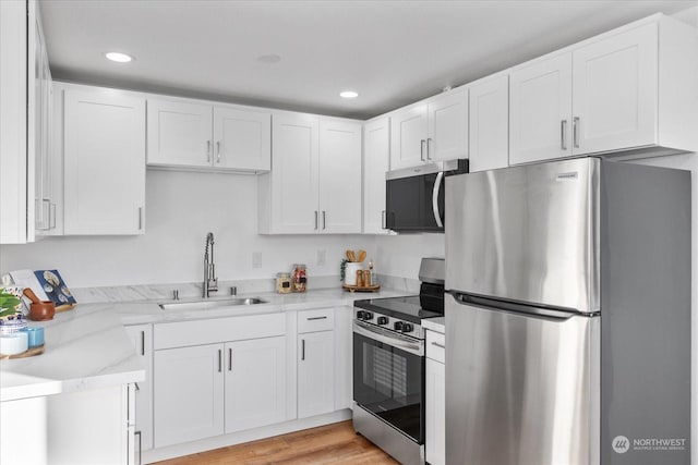 kitchen with white cabinetry, appliances with stainless steel finishes, light hardwood / wood-style floors, and sink