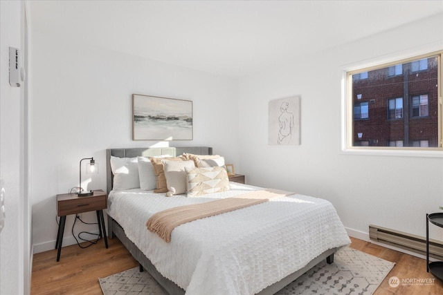 bedroom with hardwood / wood-style flooring and baseboard heating