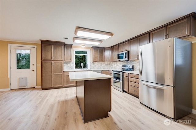 kitchen featuring stainless steel appliances, a kitchen island, a wealth of natural light, and backsplash