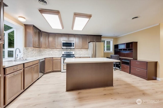 kitchen featuring appliances with stainless steel finishes, a center island, sink, and decorative backsplash