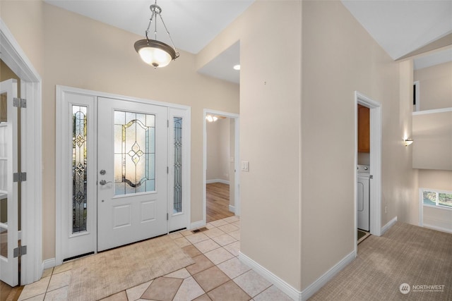 entrance foyer with washer / dryer, light tile patterned floors, and lofted ceiling