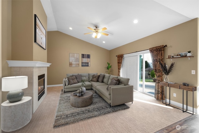 living room featuring ceiling fan, vaulted ceiling, and a tile fireplace