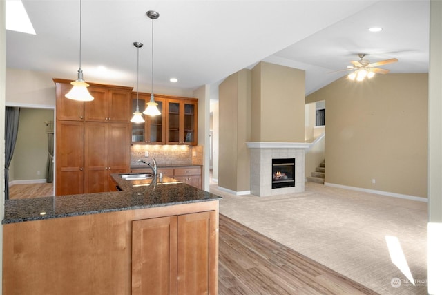 kitchen with pendant lighting, a fireplace, sink, and dark stone countertops