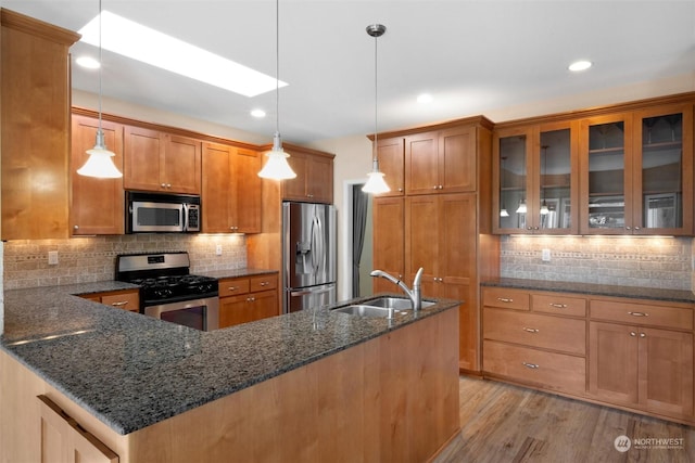 kitchen with stainless steel appliances, sink, pendant lighting, and dark stone counters