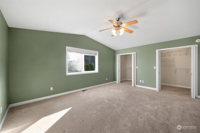 unfurnished bedroom with vaulted ceiling, two closets, light colored carpet, and ceiling fan