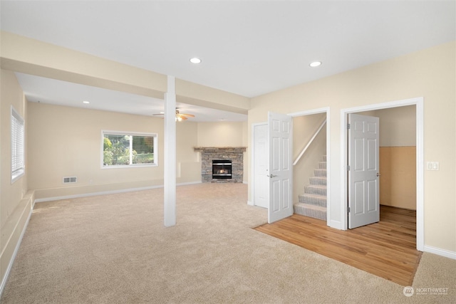 basement with ceiling fan, a fireplace, and light carpet