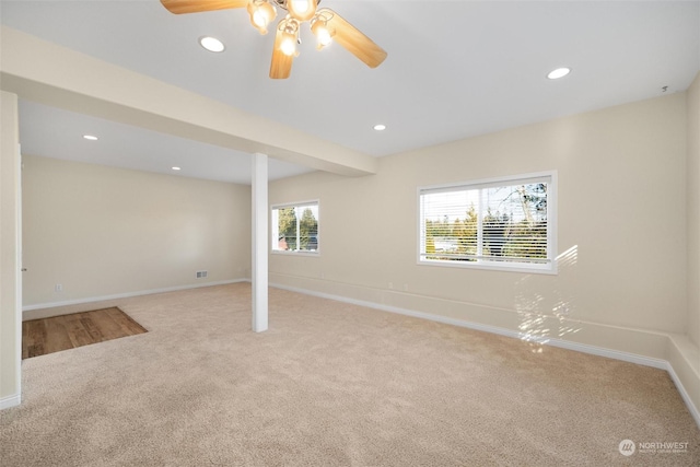 basement featuring light colored carpet and ceiling fan