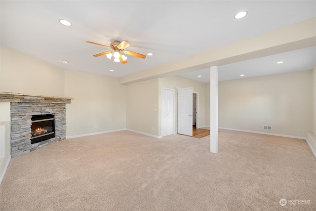 unfurnished living room featuring ceiling fan, light colored carpet, and a fireplace