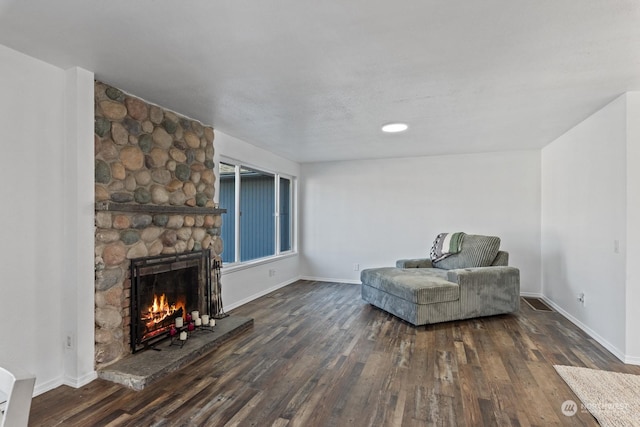 sitting room with dark hardwood / wood-style flooring and a stone fireplace