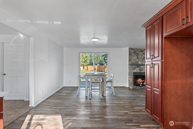 dining space featuring a stone fireplace and dark hardwood / wood-style flooring