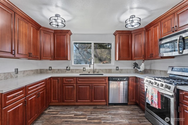 kitchen with sink, dark wood-type flooring, stainless steel appliances, and a textured ceiling