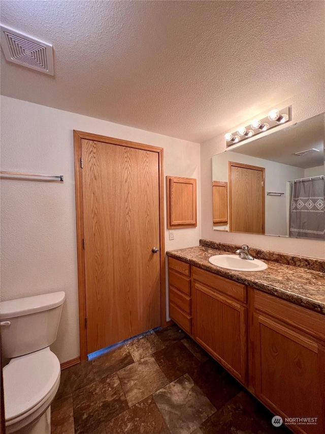 bathroom featuring vanity, toilet, and a textured ceiling