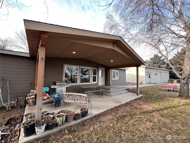 back of property featuring a garage, a yard, and a patio area