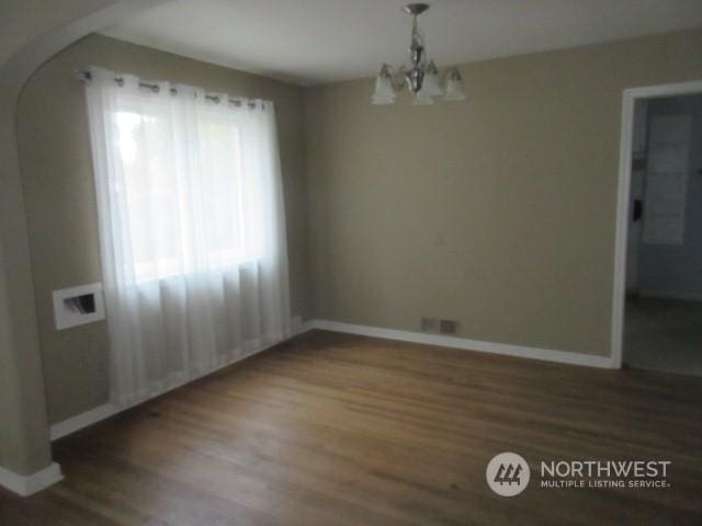 unfurnished dining area with dark wood-type flooring, vaulted ceiling, and an inviting chandelier