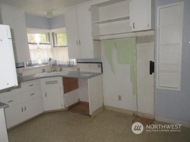 kitchen with white cabinetry, white refrigerator, and sink