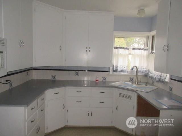 kitchen with tasteful backsplash, sink, and white cabinets