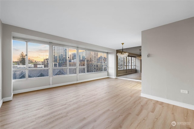 unfurnished room with a chandelier, a wealth of natural light, and light hardwood / wood-style floors