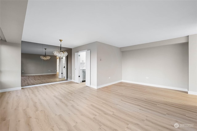 unfurnished living room featuring an inviting chandelier and light hardwood / wood-style floors