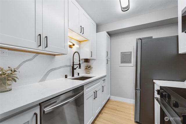 kitchen with light wood-type flooring, appliances with stainless steel finishes, sink, and white cabinets