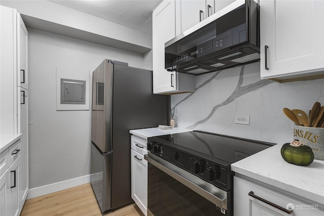 kitchen featuring light stone counters, backsplash, range with electric cooktop, and white cabinets