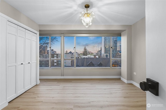 unfurnished dining area featuring an inviting chandelier and light hardwood / wood-style flooring