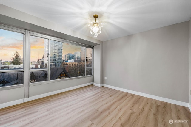 spare room featuring an inviting chandelier and wood-type flooring